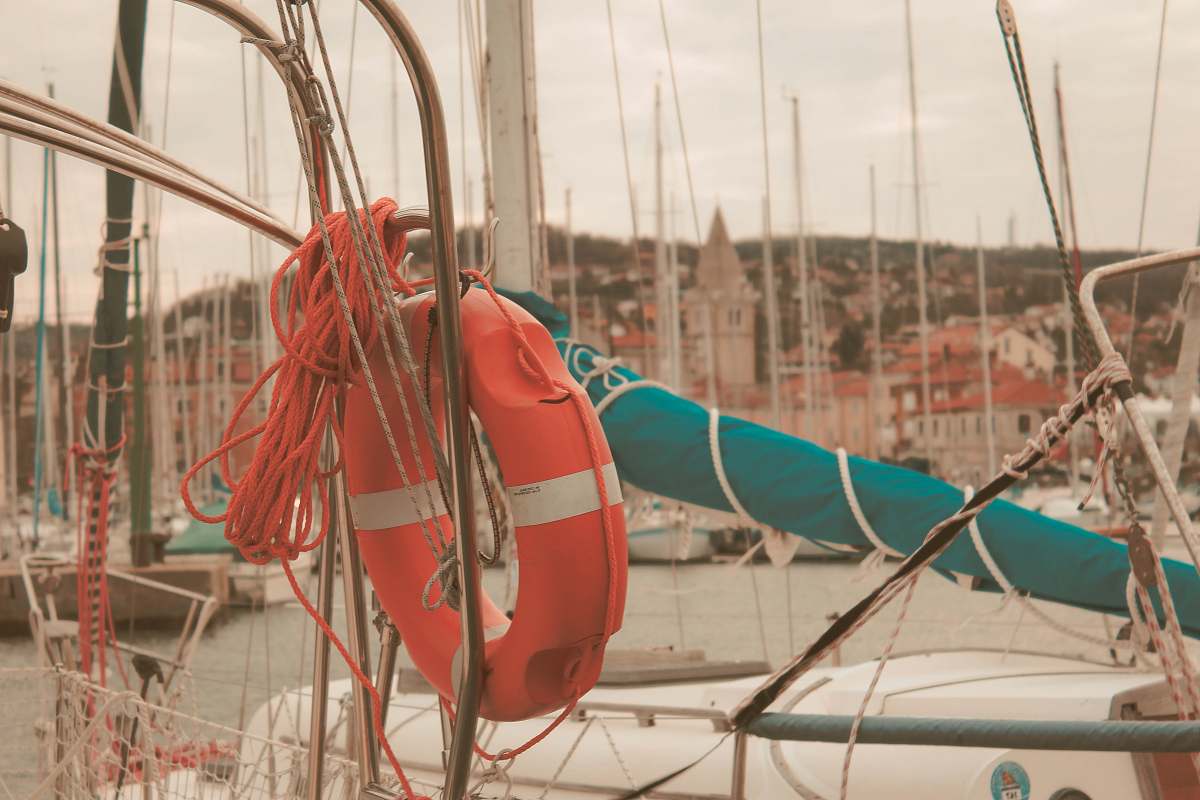 life buoy orange and white inflatable float ring tied to boat during daytie dinghy